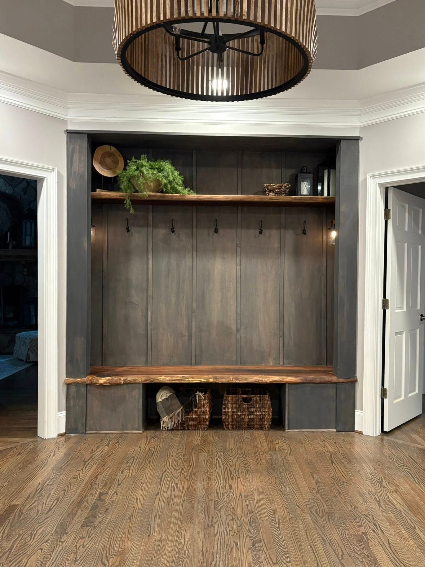 Custom mudroom built-in with stained wood bench and panel finish