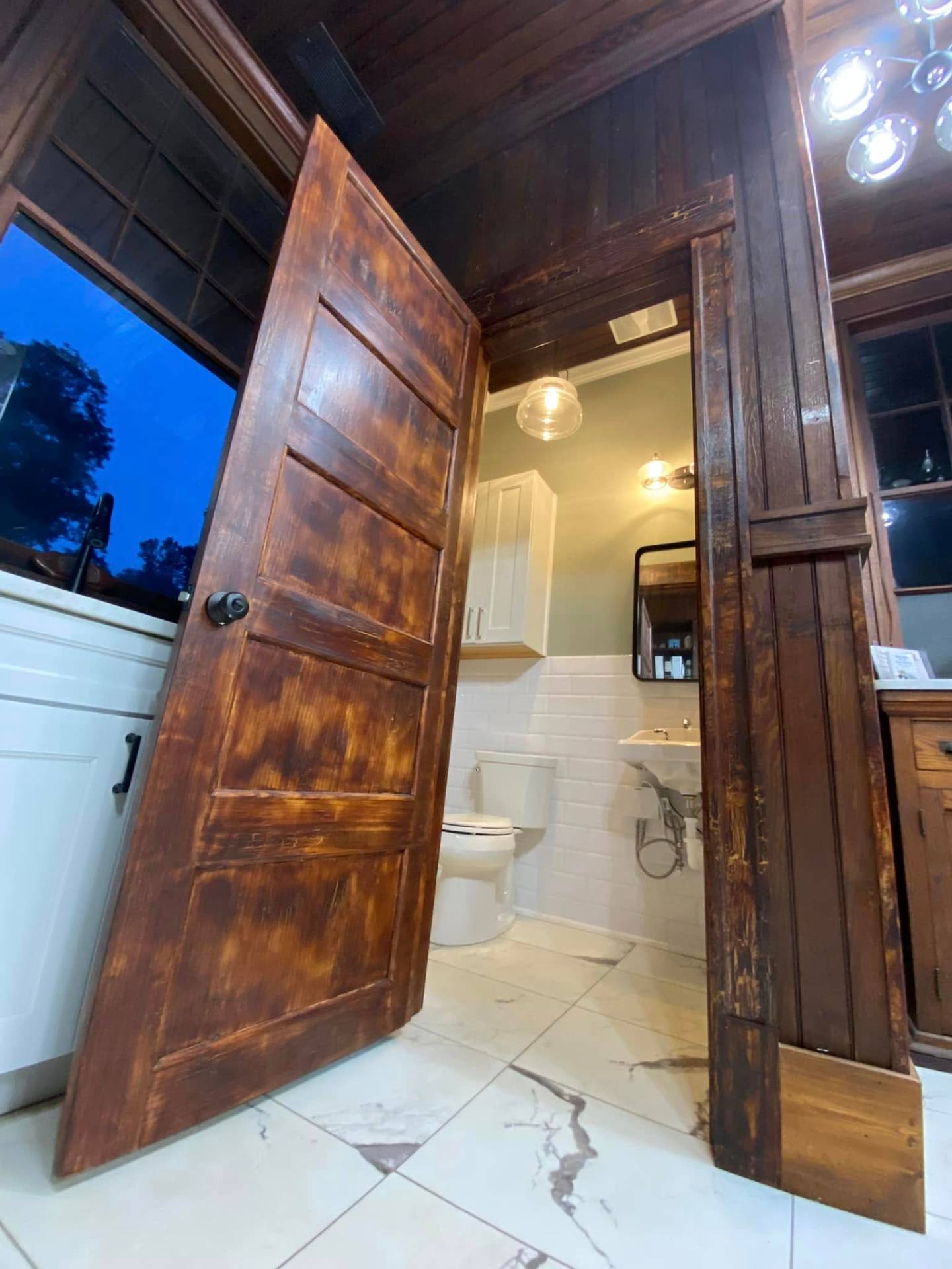Hand-finished custom stained wood door installed in a renovated bath